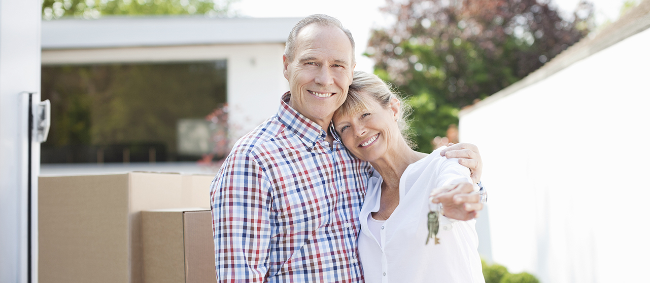 Photo of couple hugging near stack of moving boxes