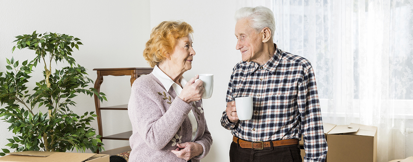 Photo of elderly couple in living room with boxes